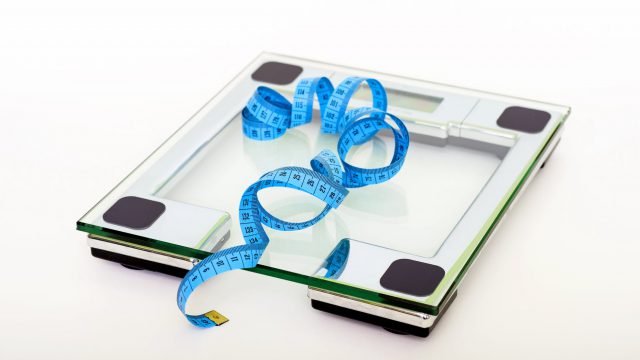 blue tape measuring on clear glass square weighing scale